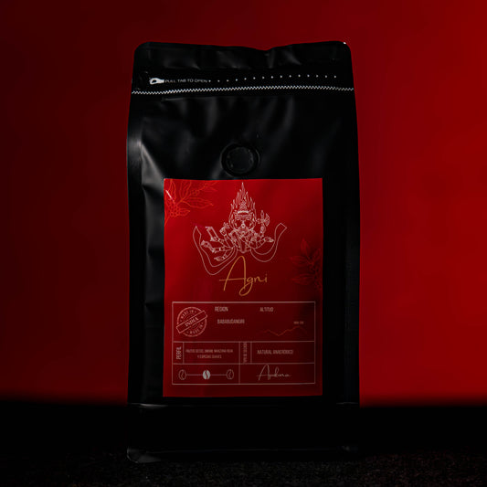 Bolsa de café de especialidad Agni de Apukuna Coffee, un café indio de la región Baba Budangiri con perfil especiado, exhibido sobre fondo rojo intenso
